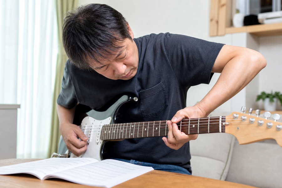 ネックを見つめ肘が張った中年男性